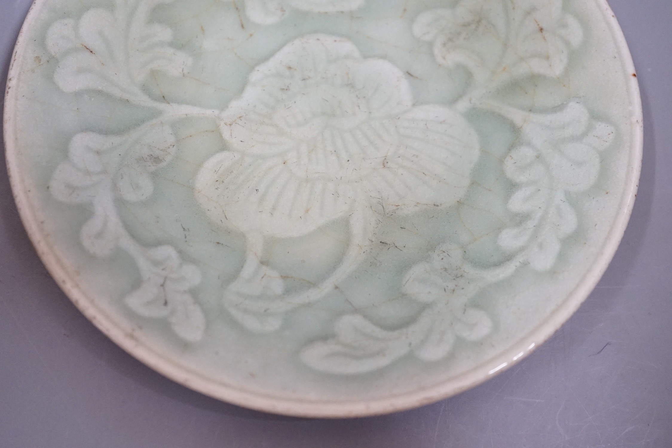 A Chinese carved celadon dish, Qing dynasty, 15cm diameter